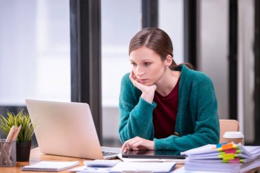 İş kadınları, ofiste dizüstü bilgisayar ve kağıt belgeler önünde çalışmakla strese girerler. İş konsepti.