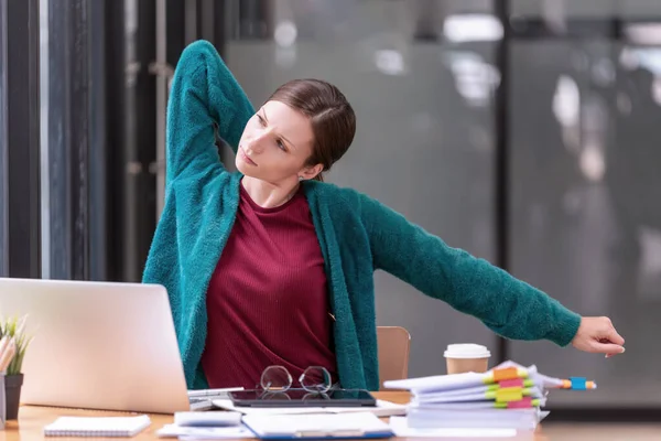 Young businesswoman office worker stretching lazily and forth relieves pain at office table workplace, feeling overworked. office syndrome concep