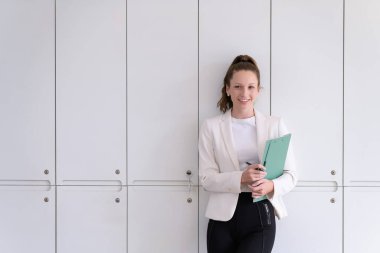 Elinde evrak işleriyle büroda duran güzel ve gülümseyen bir iş kadını. Ticaretin gelişigüzel ve başarılı kavramı