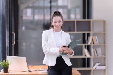 Elinde evrak işleriyle büroda duran güzel ve gülümseyen bir iş kadını. Ticaretin gelişigüzel ve başarılı kavramı