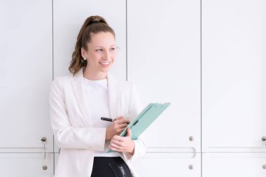 Elinde evrak işleriyle büroda duran güzel ve gülümseyen bir iş kadını. Ticaretin gelişigüzel ve başarılı kavramı