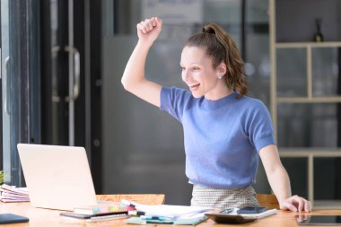 Mutlu iş kadını iş yerindeki iyi haberlere sevinçle gülüyor, dizüstü bilgisayara zevkle bakıyor, heyecanlanıyor. Ticaretin gelişigüzel ve başarılı kavramı