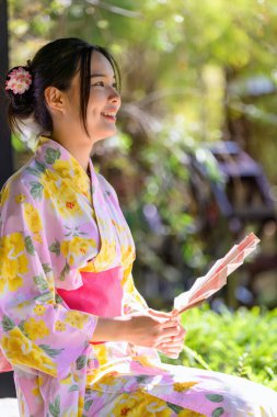 Geleneksel Japon kimonosu ya da yukata giyen genç kadınlar parkta mutlu ve neşelidir. Japon geleneksel yaz elbisesi.