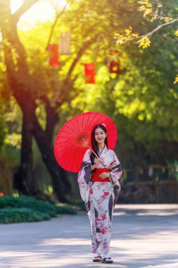 Geleneksel Japon kimonosu ya da şemsiyesi olan genç bir kadın parkta mutlu ve neşelidir. Japon geleneksel yaz elbisesi.