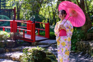 Geleneksel Japon kimonosu ya da şemsiyesi olan genç bir kadın parkta mutlu ve neşelidir. Japon geleneksel yaz elbisesi.