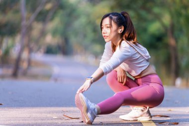 Genç bir kadın güneşli bir günde halka açık bir parkta egzersiz yapıyor. Sağlıklı yaşam tarzı ve refah bir kavramdır.