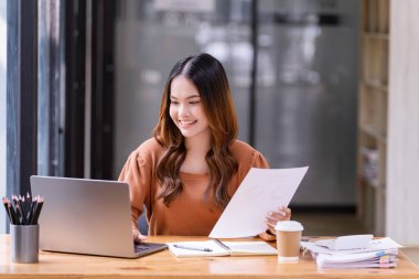 Ofisteki bir dizüstü bilgisayarın önünde çalışan genç bir kadın. Ticaretin gelişigüzel ve başarılı kavramı
