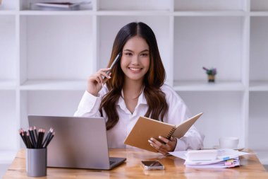 Ofisteki bir dizüstü bilgisayarın önünde çalışan genç bir kadın. Ticaretin gelişigüzel ve başarılı kavramı
