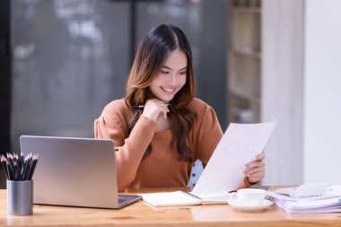 Ofisteki bir dizüstü bilgisayarın önünde çalışan genç bir kadın. Ticaretin gelişigüzel ve başarılı kavramı