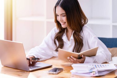 Ofisteki bir dizüstü bilgisayarın önünde çalışan genç bir kadın. Ticaretin gelişigüzel ve başarılı kavramı