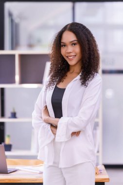 Ofis odasında neşeli, genç bir kadın. İş yerinde kendine güvenen olgun bir iş kadını.