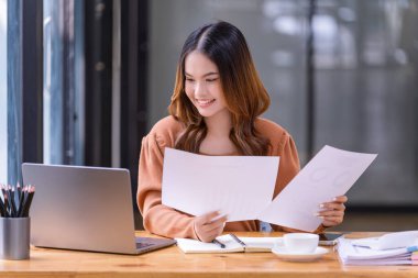 Ofisteki bir dizüstü bilgisayarın önünde çalışan genç bir kadın. Ticaretin gelişigüzel ve başarılı kavramı