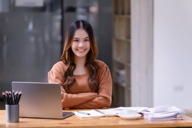 Ofisteki bir dizüstü bilgisayarın önünde güzel bir pozda oturan genç bir kadın. İş dünyasının gelişigüzel kavramı