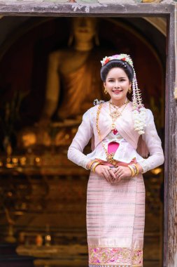 A young Thai woman dressed in traditional Northern Thailand culture costume visits a temple in Chiang Mai, Thailand. Asian young Women in traditional costumes at the Thai Temple clipart