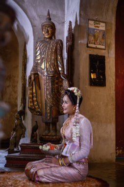 A young Thai woman dressed in traditional Northern Thailand culture costume visits a temple in Chiang Mai, Thailand. Asian young Women in traditional costumes at the Thai Temple clipart