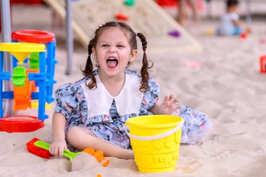 Oyun sahasında kumlarda oynayan tatlı bir kız. Çocukların oyun parkında eğlenmesi kavramı