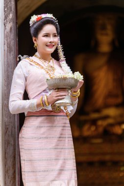 A young Thai woman dressed in traditional Northern Thailand culture costume visits a temple in Chiang Mai, Thailand. Asian young Women in traditional costumes at the Thai Temple clipart