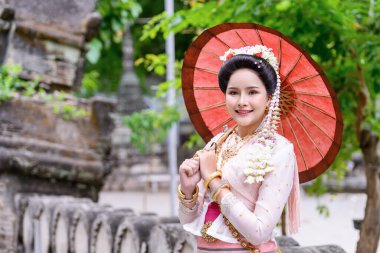 Geleneksel Kuzey Tayland kültürü kostümü giymiş genç bir Taylandlı kadın Tayland, Chiang Mai 'deki bir tapınağı ziyaret ediyor. Tayland Tapınağı 'nda geleneksel kostümlü Asyalı genç kadınlar