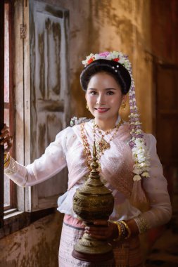 A young Thai woman dressed in traditional Northern Thailand culture costume visits a temple in Chiang Mai, Thailand. Asian young Women in traditional costumes at the Thai Temple clipart