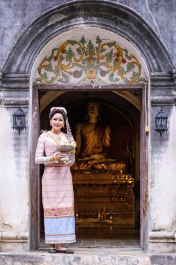 Geleneksel Kuzey Tayland kültürü kostümü giymiş genç bir Taylandlı kadın Tayland, Chiang Mai 'deki bir tapınağı ziyaret ediyor. Tayland Tapınağı 'nda geleneksel kostümlü Asyalı genç kadınlar