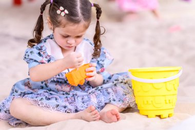 Cute girl having fun playing in the sand in the playground. Concept of children having fun on playground equipment clipart