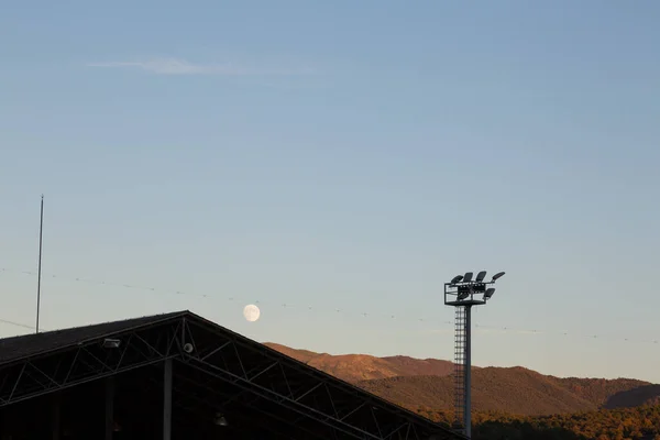 landscape at sunset with sports facilities and full moon in the background in clear sky