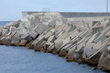 Büyük beton yığınları bir liman dalgakıranı oluşturuyor.
