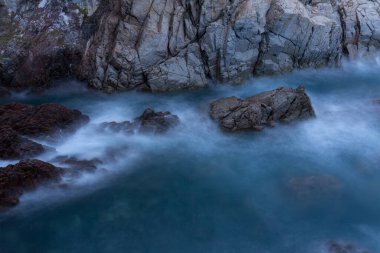 Günbatımında Akdeniz kıyılarındaki kayalara çarpan dalgalı deniz