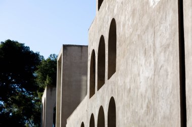 Yaratıcı açık gri beton kemerlerle dolu yapı, şekli tanımlayan sert gölgelerle, boşluklar ve odalar yaratıyor..