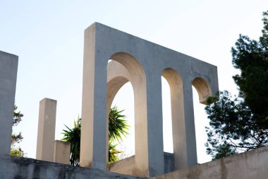 Yaratıcı açık gri beton kemerlerle dolu yapı, şekli tanımlayan sert gölgelerle, boşluklar ve odalar yaratıyor..