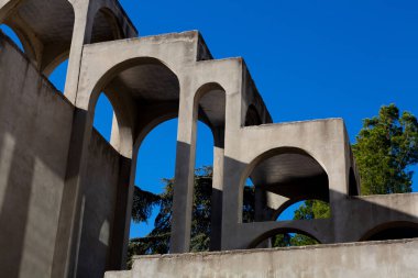 Yaratıcı açık gri beton kemerlerle dolu yapı, şekli tanımlayan sert gölgelerle, boşluklar ve odalar yaratıyor..