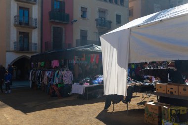 Açık mavi gökyüzünün altında, kurbanın resimli kasaba meydanında hareketli bir açık hava pazarı.