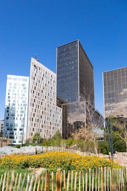 Güneşli bir günde çevresi yeşil ağaçlar ve çimlerle çevrili modern ofis binalarıyla dolu bir iş bölgesi.