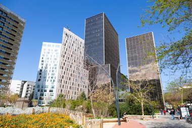 Güneşli bir günde çevresi yeşil ağaçlar ve çimlerle çevrili modern ofis binalarıyla dolu bir iş bölgesi.