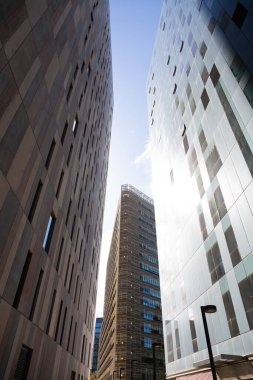 Güneşli bir günde çevresi yeşil ağaçlar ve çimlerle çevrili modern ofis binalarıyla dolu bir iş bölgesi.