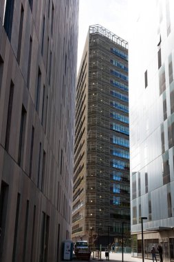 Güneşli bir günde çevresi yeşil ağaçlar ve çimlerle çevrili modern ofis binalarıyla dolu bir iş bölgesi.