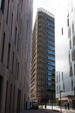 Güneşli bir günde çevresi yeşil ağaçlar ve çimlerle çevrili modern ofis binalarıyla dolu bir iş bölgesi.