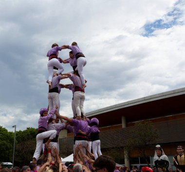 Geleneksel beyaz pantolon ve mor gömlekler giyen Katalan halkı, yerel festivaller için bir insan kulesi, bir castell inşa ediyorlar.