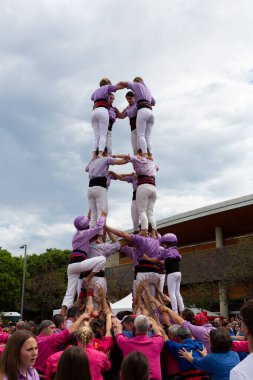 Geleneksel beyaz pantolon ve mor gömlekler giyen Katalan halkı, yerel festivaller için bir insan kulesi, bir castell inşa ediyorlar.