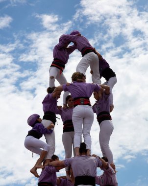 Geleneksel beyaz pantolon ve mor gömlekler giyen Katalan halkı, yerel festivaller için bir insan kulesi, bir castell inşa ediyorlar.