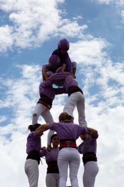 Geleneksel beyaz pantolon ve mor gömlekler giyen Katalan halkı, yerel festivaller için bir insan kulesi, bir castell inşa ediyorlar.