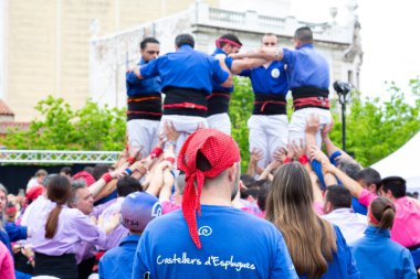 Geleneksel beyaz pantolon ve mor gömlekler giyen Katalan halkı, yerel festivaller için bir insan kulesi, bir castell inşa ediyorlar.