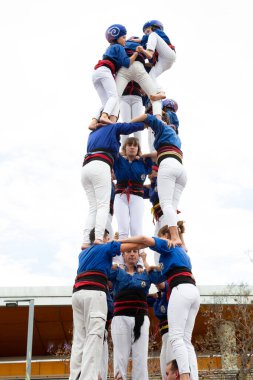 Geleneksel beyaz pantolon ve mor gömlekler giyen Katalan halkı, yerel festivaller için bir insan kulesi, bir castell inşa ediyorlar.