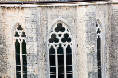 Güneş ışığı taştan yapılmış eski bir binanın üç gotik kilise penceresinden geçiyor.