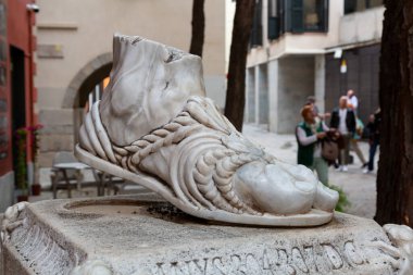 Arka planda sandalet ve turistlerin yürüdüğü antik Roma mermer ayak heykeli