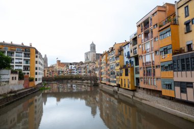 Onyar nehrinin Pont de les peixateries 'in altından akışını ve arka planda Saint Feliu Bazilikası olan Girona, Katalonya