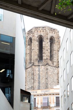 Antik taş kule kemerli pencerelerle modern binalar ve şehir merkezleri arasında birleştiriliyor. Tarihi ve çağdaş mimari arasındaki zıtlığı sergiliyor.