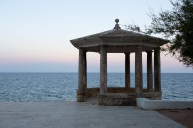 Uçuruma tünemiş taştan bir taraçanın sakin manzarası. Güneş batarken denizin engin genişliğine bakıyor.