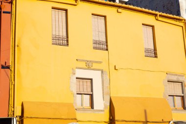 Geleneksel sarı ve beyaz binalar küçük bir İspanyol kasabasında mavi gökyüzünün altında yan yana duruyorlar.