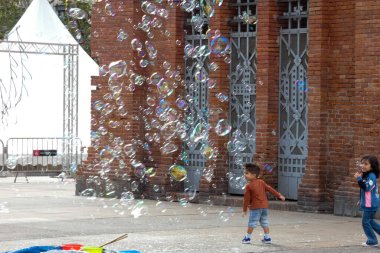 Barselona 'da bir parkta dev sabun köpükleri yapan bir sokak şarkıcısını izleyen turistler